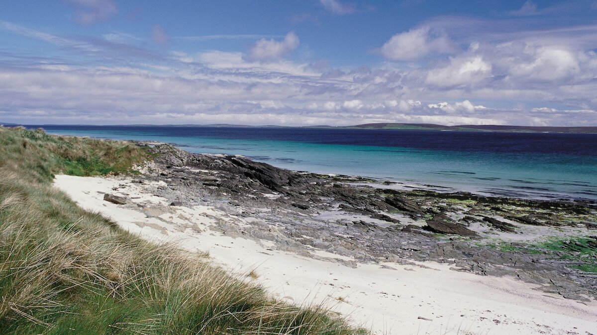 A sweeping sandy beach with rocky outcrop and turquoise sea