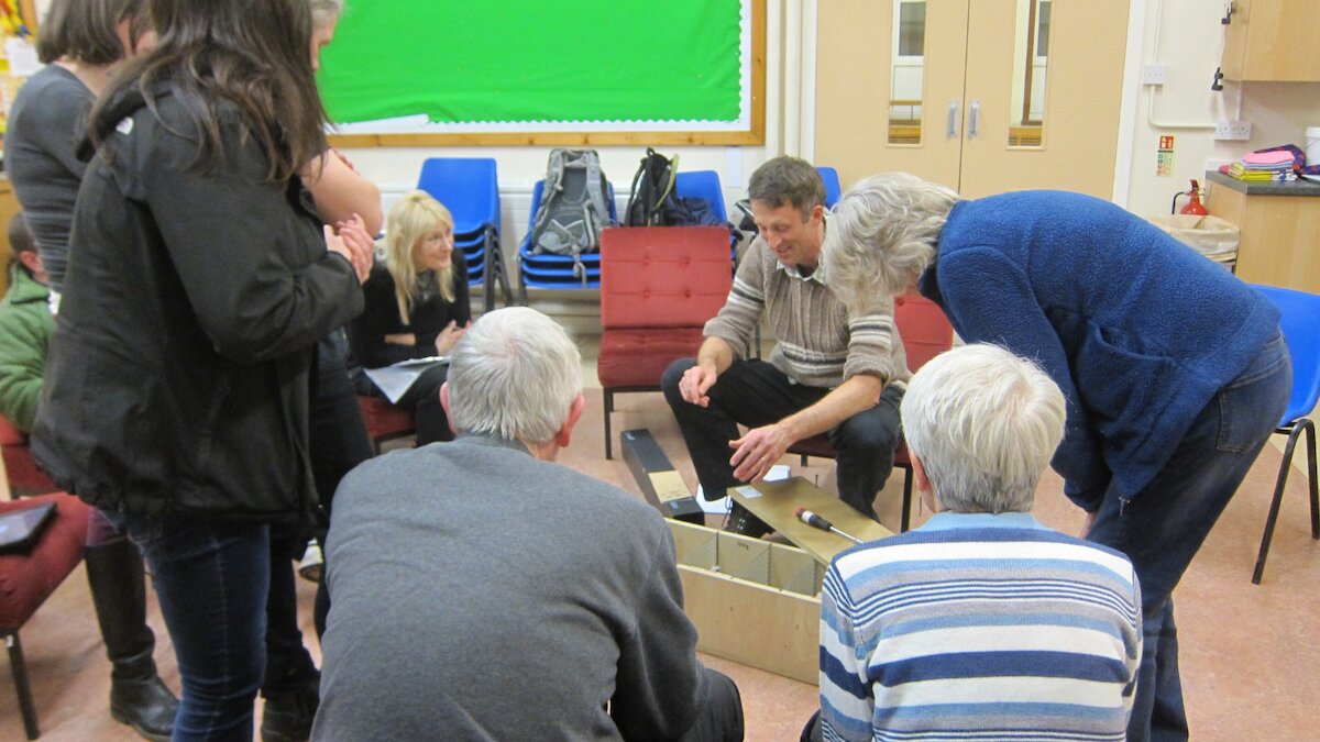 A group of people are shown how a trap works inside a school room
